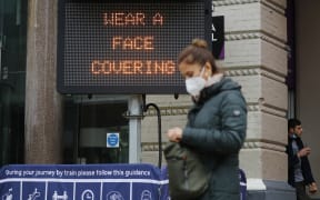 A pedestrian walks past a sign displaying a message to wear a face covering, outside Charing Cross station in central London on 14 October 2020.