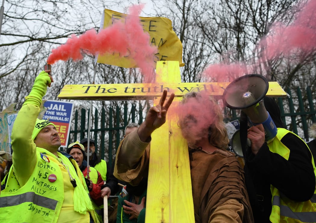 A supporter of WikiLeaks founder Julian Assange, holds a flare as he calls for Assange's freedom outside Woolwich Crown Court