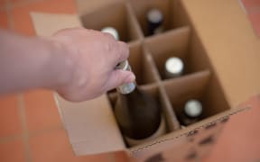 Person taking wine bottle out of box.