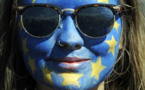 A festival-goer with a European flag painted on her face poses for a photograph on day three of the Glastonbury Festival.