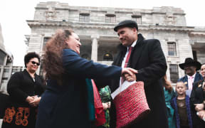 Toni Boynton from Te Rōpū Tautoko Māori handing the petition to Labour MP Tamati Coffey.