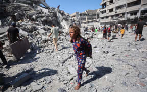 Displaced Palestinians salvage items from the rubble of the al-Ghafari tower after it was destroyed in Israeli strikes in Gaza City.