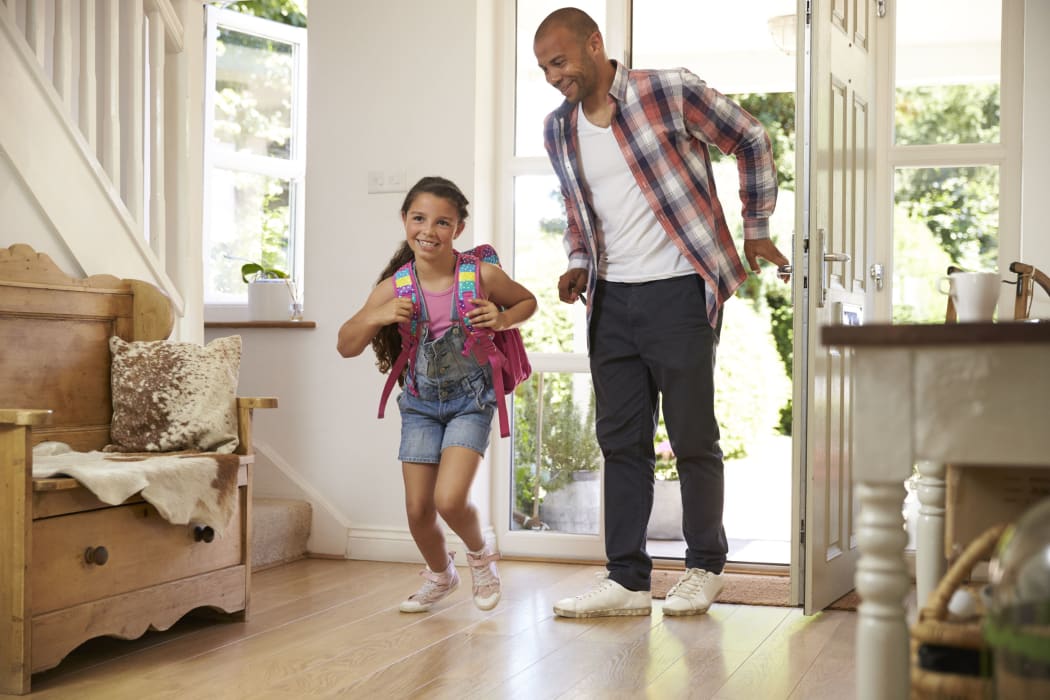 A photo of an excited girl returning home from school with her father