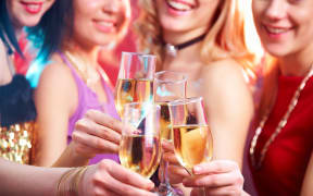 Women clink glasses of champagne at a party
