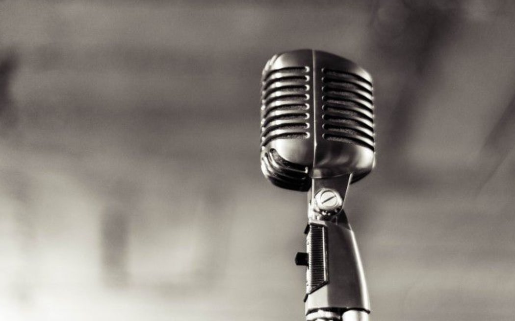 Black and white picture of an old 1960s style microphone on a stand