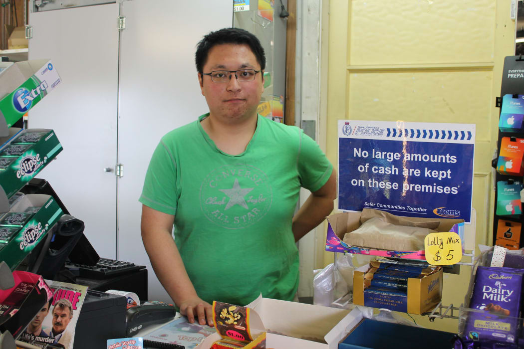 A photo of Adam Du at the counter of the Burwood's Lake Terrace Stationery and Dairy which was robbed earlier this year.