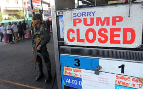 A member of Sri Lankan security personnel stands guard outside a fuel station that ran out of gasoline in Colombo on 27 June, 2022.