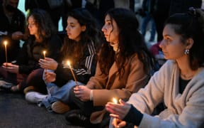 Students hold candles outside the Hellenic Train headquarters in Athens on 1 March, 2023, during a tribute to the victims of a deadly train crash near the city of Larissa, central Greece. The Greek government announced 3 days of national mourning.