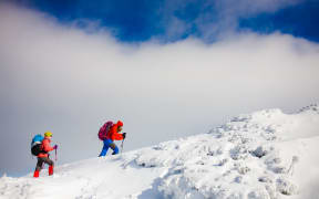 Two girls go on a snowy hill during a mountaineering adventure in the mountains.