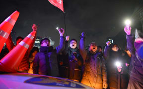 People gesture as they gather outside the National Assembly in Seoul on December 4, 2024, after South Korea President Yoon Suk Yeol declared martial law. - South Korea's President Yoon Suk Yeol on December 3 declared martial law, accusing the opposition of being "anti-state forces" and saying he was acting to protect the country from "threats" posed by the North. (Photo by Anthony WALLACE / AFP)