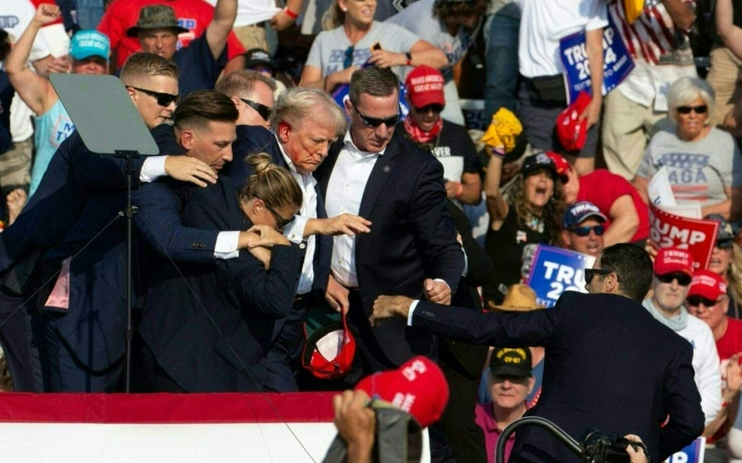 Republican candidate Donald Trump is seen with blood on his face surrounded by secret service agents as he is taken off the stage at a campaign event in Butler, Pennsylvania, 13 July, 2024.