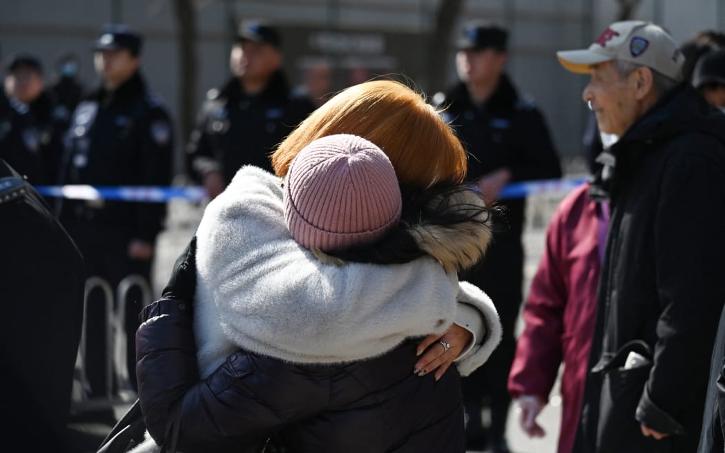 Relatives of passengers who were on board the missing Malaysia Airlines flight MH370 embrace during a gathering outside the Malaysian embassy in Beijing on 8 March, 2024, on the 10th anniversary of the flight’s disappearance.