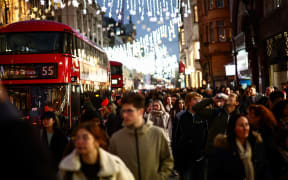 Shoppers walk under neath the Christmas lights on Oxford Street, in central London, on December 13, 2024. (Photo by HENRY NICHOLLS / AFP)