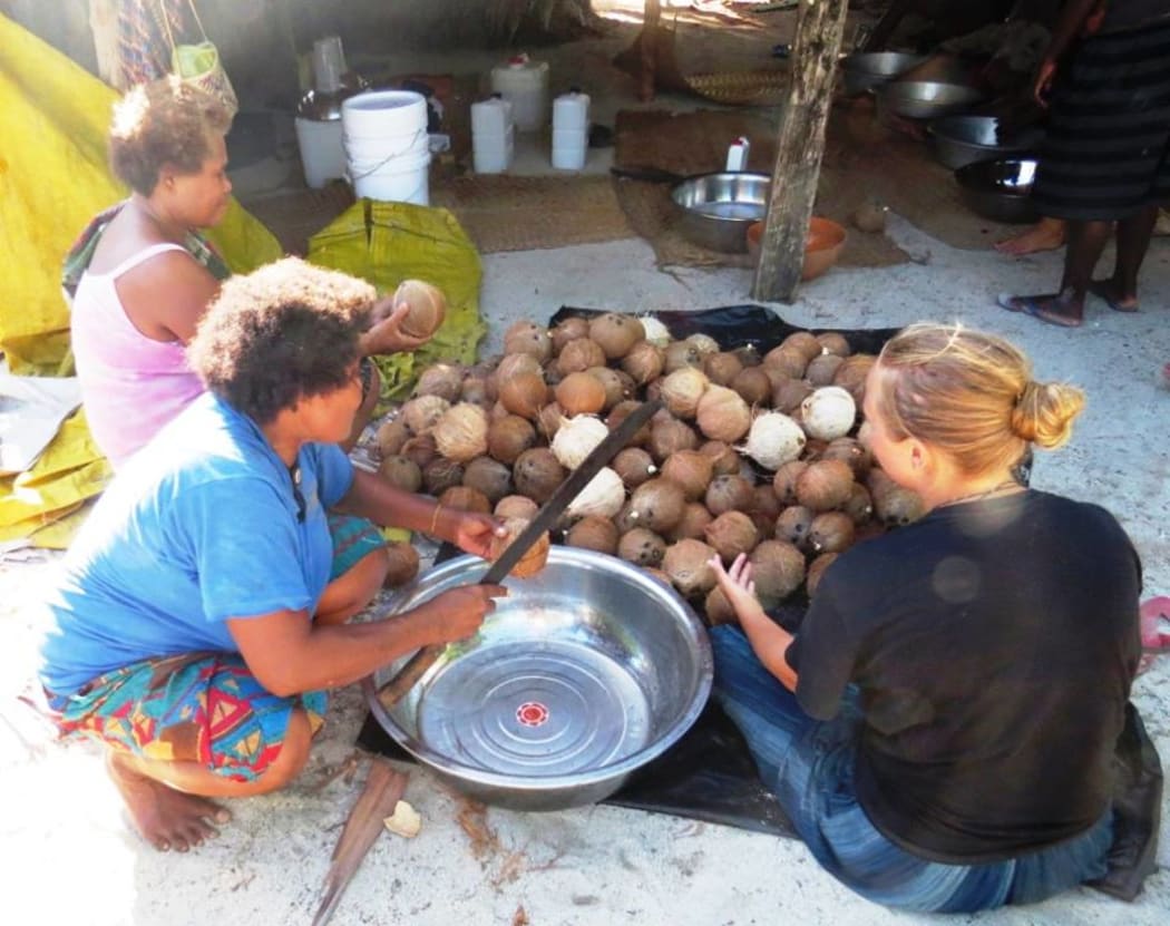 Stage one of making Virgin Coconut Oil, cracking the nuts at Ngadeli village, Reef Islands.