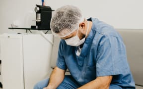A man in hospital scrubs wit his head down