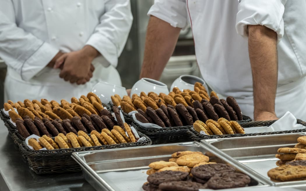 Chef finishing baked cookies in commercial stainless steel kitchen