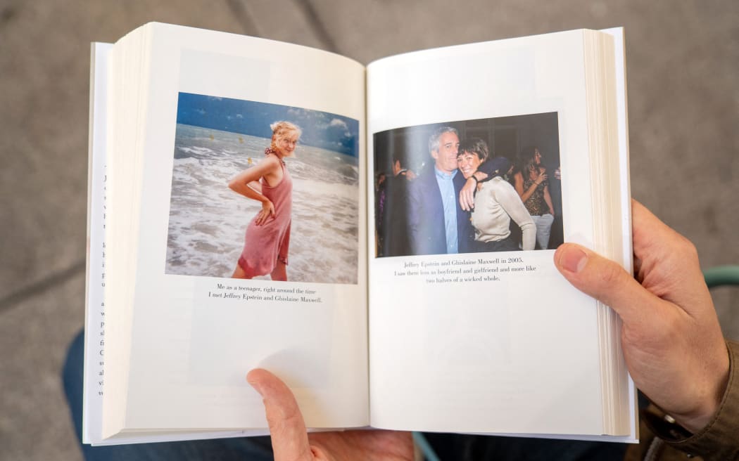 A person holds open pages of the book "Nobody's Girl - A Memoir of Surviving Abuse and Fighting for Justice" by Virginia Roberts Giuffre, displaying photos published in the book, as it is pictured in central London on October 21, 2025, on the day of its release in the UK.
