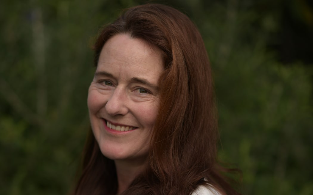 A woman with long brown dark hair smiles at the camera.