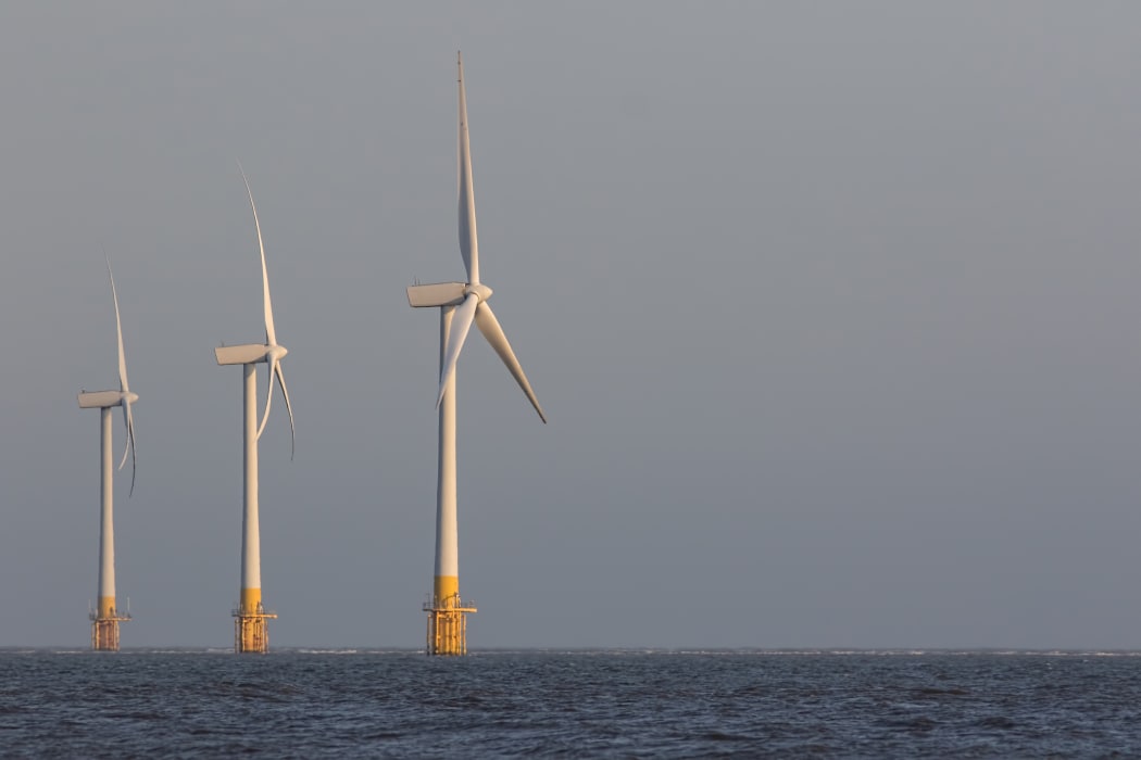 Offshore wind turbines. Wind farm on the sea horizon. Clean energy. Profile of three massive sustainable resource power generation turbines.