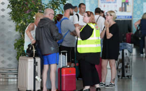 A British government official speaks to tourists, flying with Thomas Cook, as they queue at the Enfidha International airport on September 23, 2019, on the outskirts of Sousse south of the capital Tunis.