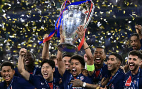 Paris Saint-Germain's Brazilian defender #05 Marquinhos lifts the trophy next to his teammates after the UEFA Champions League final football match between Paris Saint-Germain (PSG) and Inter Milan in Munich, southern Germany on May 31, 2025. (Photo by Marco BERTORELLO / AFP)