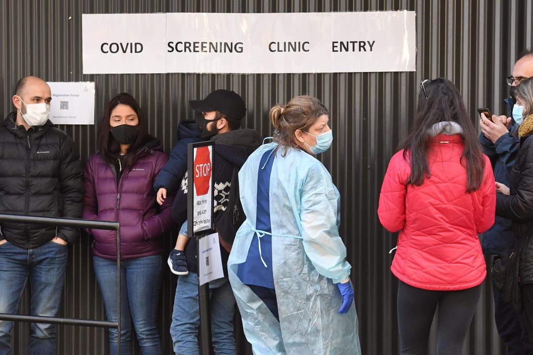 A medical worker (C) speaks to people queueing outside a COVID-19 coronavirus testing venue at The Royal Melbourne Hospital in Melbourne on July 16, 2020.