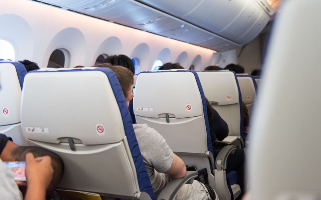 Man asleep in seat on airplane during travel abroad in aircraft.