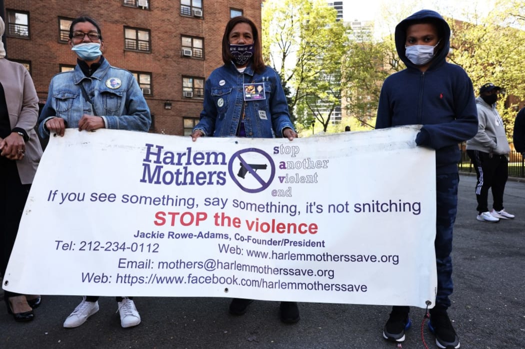 Margie Rodrigues, Milagros Ortega and Gino Myers, 10, hold a banner as they join others before a peace walk to denounce the rise of gun violence in the city in the Harlem neighborhood on April 30, 2021 in New York City.