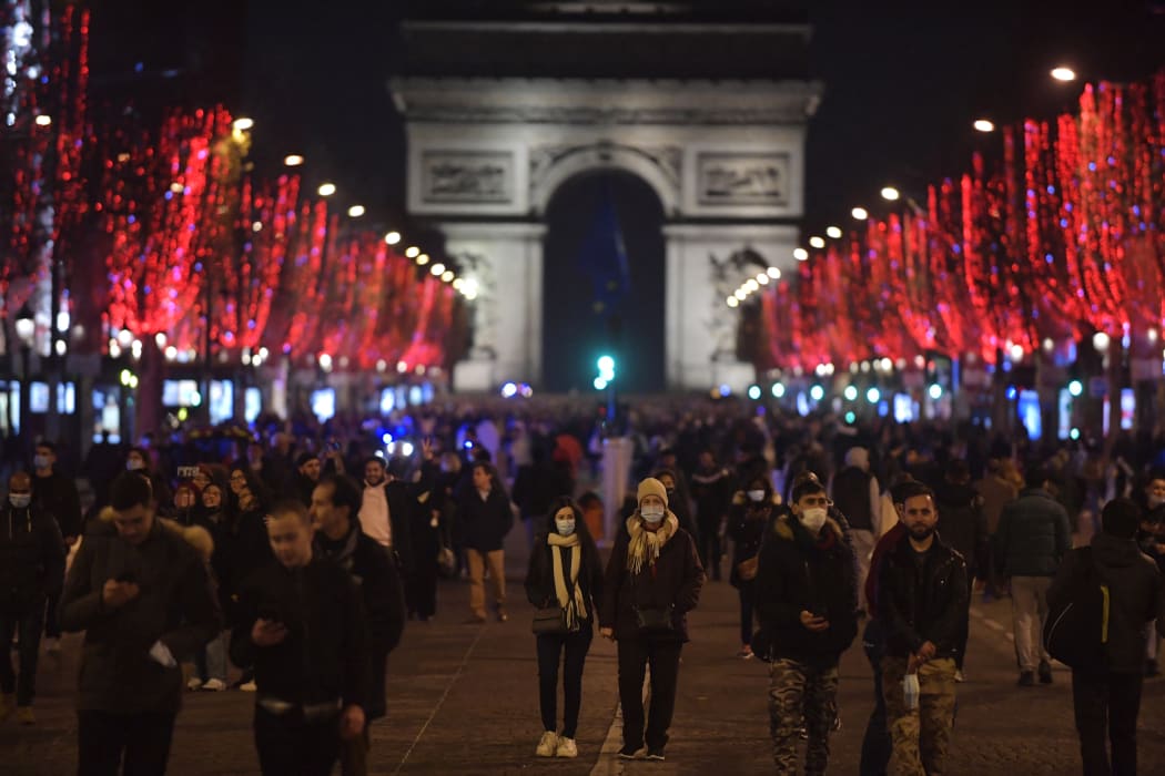 Masked pedestrians walk along the Champs-Elysees Avenue in Paris, France on New Year's Eve, 31 December 2021.