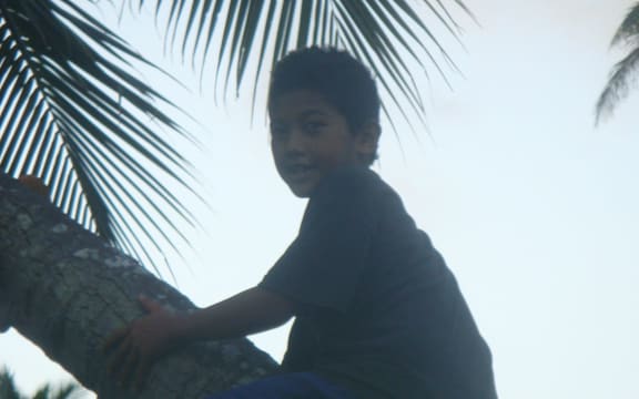 A young boy climbs a coconut tree in Tonga.