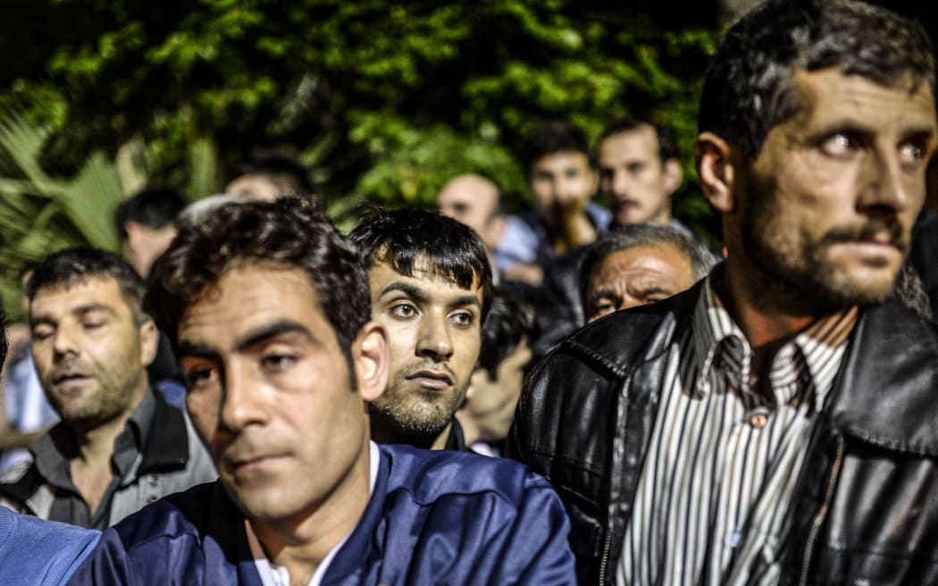 People stand in front of a hospital as they wait for news from their relatives.