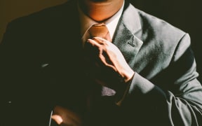 Man in suit adjusts tie