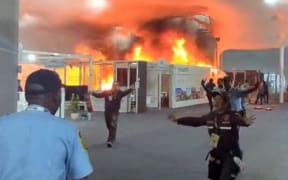 This screen grab taken from AFPTV video footage shows emergency crews battling a fire that broke out at a pavilion inside the venue of the COP30 UN Climate Change Conference in Belem, Para state, Brazil, on November 20, 2025. A fire erupted at a pavilion inside the venue of the UN's climate talks in Brazil on Thursday, prompting panicked delegates to run for the exits, AFP journalists said. Emergency crews rushed to try to put out the blaze as smoke engulfed the corridor. (Photo by AFPTV / AFP)