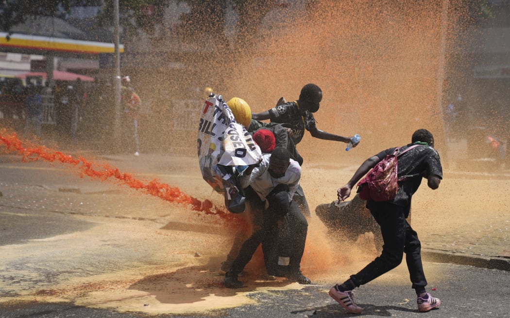 Protesters scatter as Kenya police spray water canon at them during a protest over proposed tax hikes in a finance bill in downtown Nairobi, Kenya Tuesday, June. 25, 2024. (AP Photo/Brian Inganga)