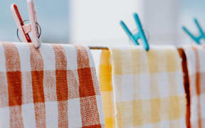 Checkered kitchen towels hanging to dry on a clothesline outdoors.