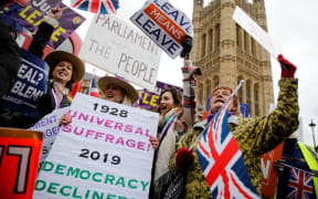 Pro-Brexit activists hold placards and wave Union flags as they demonstrate outside of the Houses of Parliament.