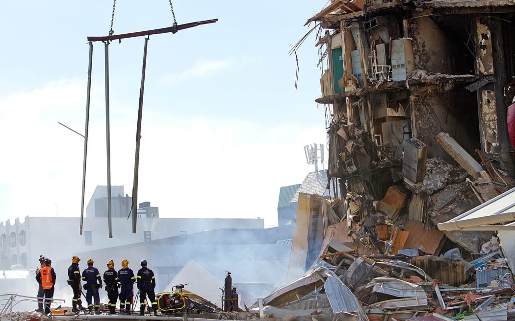 Rescuers stand at the smoking ruins of the CTV building.