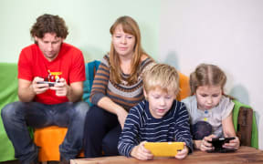 36913913 - children and husband are passionate about games in the phone, mother looking at the kids
