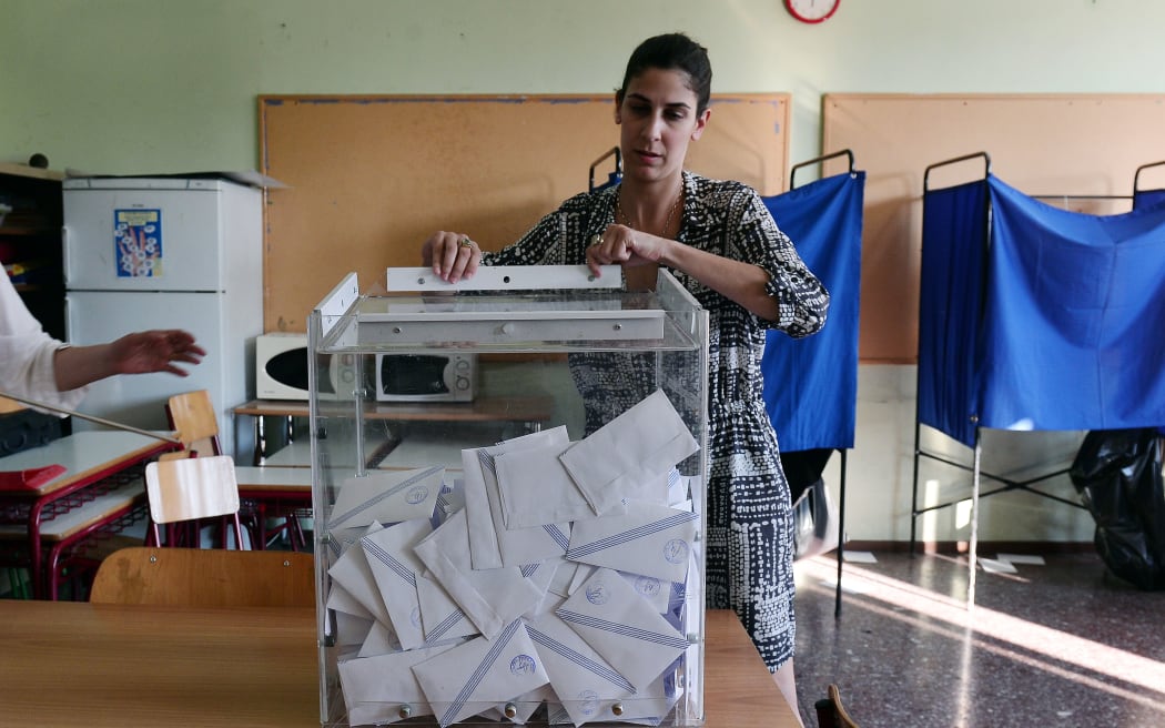 Polling station officials opens the ballot box at a polling station in Athens.