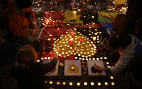 People light candles in tribute to victims at a makeshift memorial in front of the stock exchange at the Place de la Bourse in Brussels on March 22, 2016.