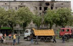 People walk past a residential building damaged during a Russian drone attack that killed two people and wounded eight others, Ukrainian officials said, in Kyiv on 7 May, 2025, amid the Russian invasion of Ukraine.