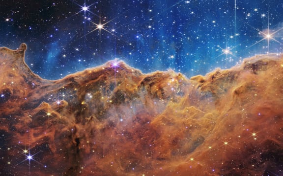 This image released by NASA on July 12, 2022, from the James Webb Space Telescope (JWST) shows a landscape of “mountains” and “valleys” speckled with glittering stars which is actually the edge of a nearby, young, star-forming region called NGC 3324 in the Carina Nebula. Captured in infrared light by the JWST, this image reveals for the first time previously invisible areas of star birth. - The JWST is the most powerful telescope launched into space and it reached its final orbit around the sun, approximately 930,000 miles from Earths orbit, in January, 2022. The technological improvements of the JWST and distance from the sun will allow scientists to see much deeper into our universe with greater detail. (Photo by Handout / NASA / AFP) / RESTRICTED TO EDITORIAL USE - MANDATORY CREDIT "AFP PHOTO / NASA" - NO MARKETING NO ADVERTISING CAMPAIGNS - DISTRIBUTED AS A SERVICE TO CLIENTS