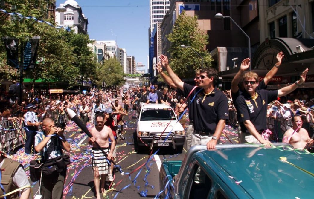 Russell Coutts (2/R) waves to the hundreds of thousands of specatators who turned up for a ticker-tape parade before the America's Cup is presented to Team New Zealand in Auckland, 04 March 2000