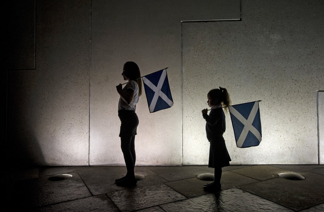 Two young girls holding saltires, watch the entertainment outside the Scottish Parliament in Edinburgh on September 18, 2014, during Scotland's independence referendum.