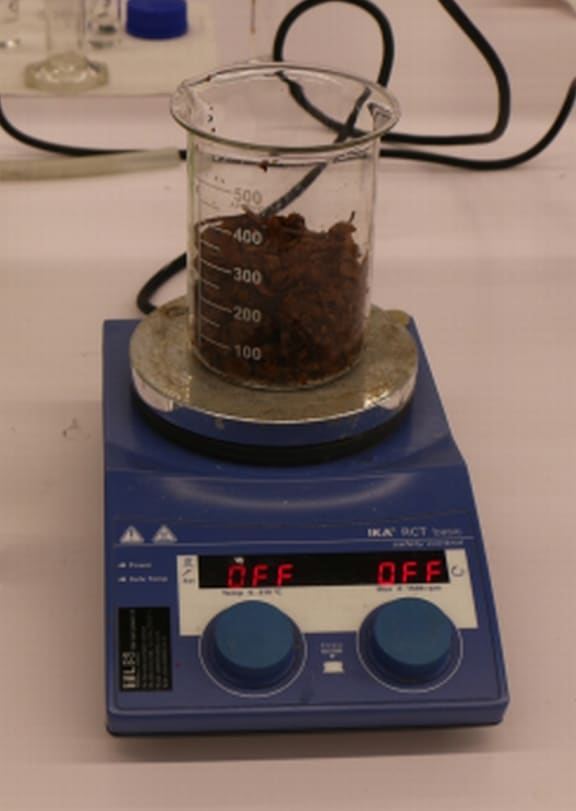 An image of the dried, tea leaf-like marc or waste in a beaker.