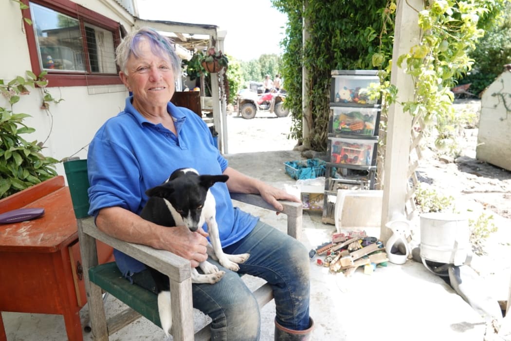 Julie Rush, with dog Jody, takes a break from cleaning up her property.