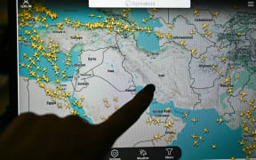 A person points at a page on the Flightradar 24 website thats shows civilian flights avoiding Iranian and Iraqi sky, in Paris on March 1, 2026. The biggest disruption to global air transport since the Covid pandemic continued on March 1, 2026, with thousands of flights affected and busy Middle Eastern hubs including Dubai and Doha shuttered as Iran lashed out after US-Israeli strikes. Iran, Iraq, Israel, Syria, Kuwait, Qatar and the United Arab Emirates had all announced at least partial closures of their skies Saturday after the US and Israel attacked Iran, bringing civilian air traffic over the Middle East to an abrupt halt. (Photo by Anna KURTH / AFP)