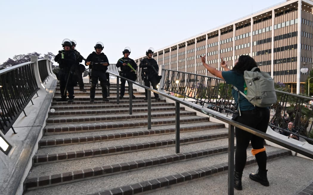 A protestor makes a rude gesture towards LAPD officers as she has to clear the area as curfew is in effect after days of protests in response to federal immigration operations in Los Angeles.