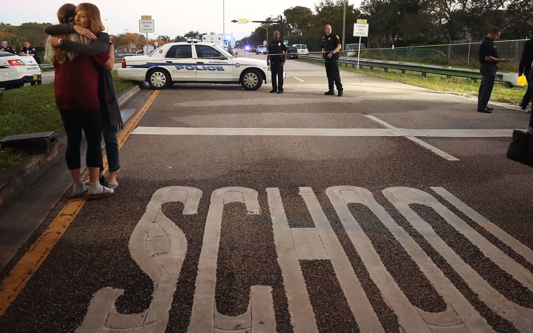 Two women hug near at the police checkpoint at the Marjory Stoneman Douglas High School, where 17 people were killed by a gunman.
