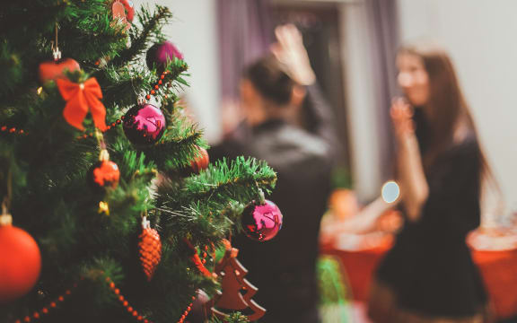 A Christmas party scene, with a decorated tree in the foreground.